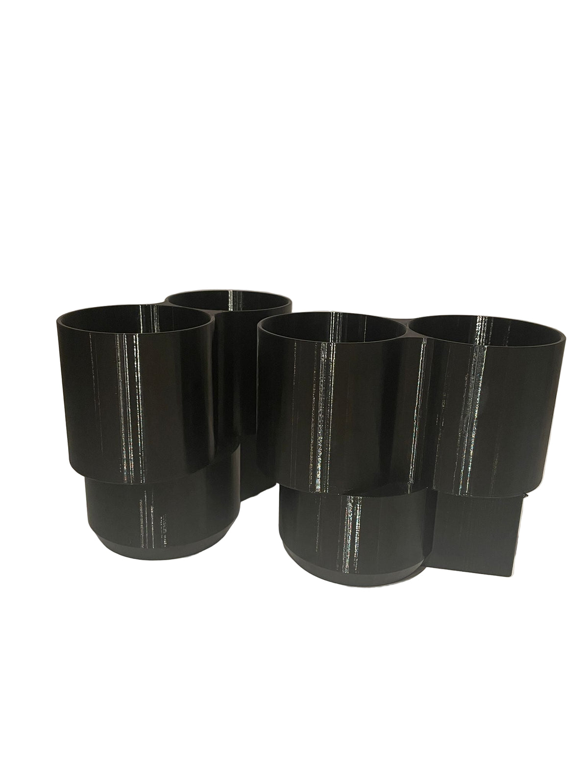 Four black cylindrical objects on a white surface with a neutral background